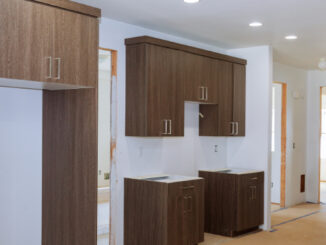 A modern kitchen under construction with dark wood cabinets, white walls, and unfinished countertops.